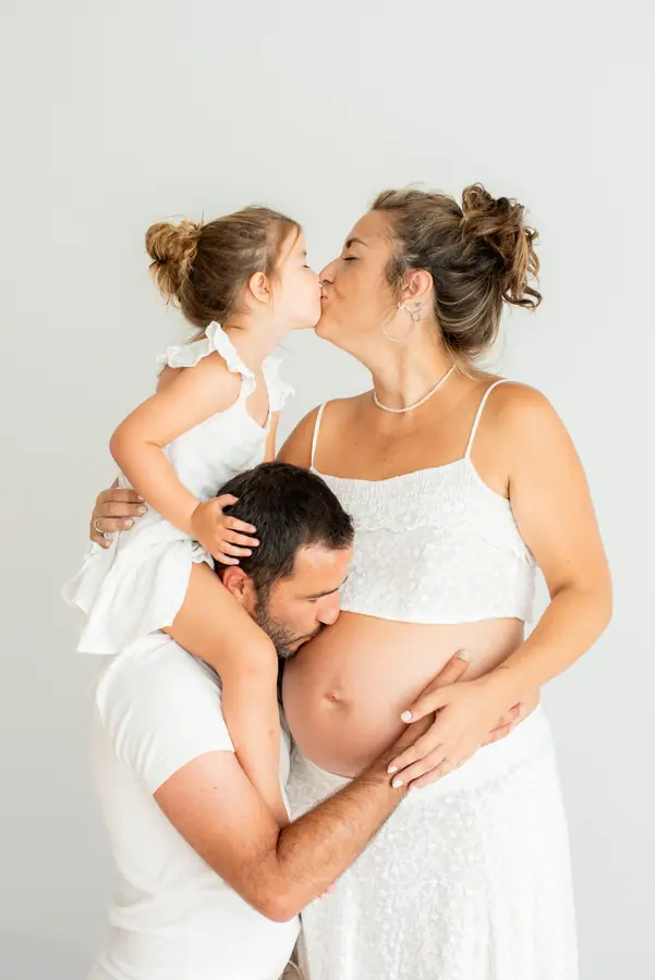 Familia besando la barriga en sesión de embarazo